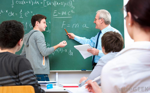 teacher assisting student at chalkboard